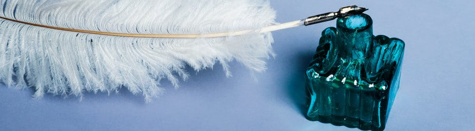 white-feather-quill-resting-on-an-ink-bottle-on-blue-background